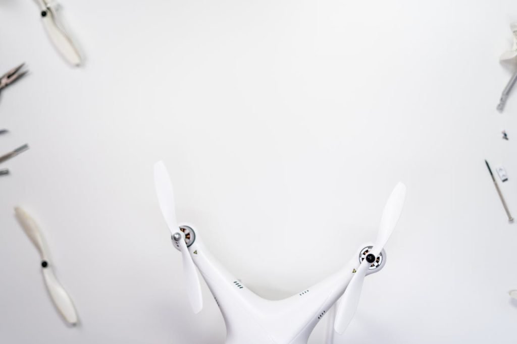 Top-down view of a white quadcopter drone with tools on a white background.